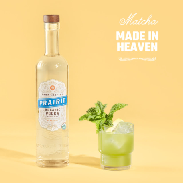 A lo-ball glass with matcha and a sprig of mint next to a bottle of Prairie Organic vodka